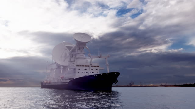 A ship with satellite dish in the sea against the cloudy sky in a day light