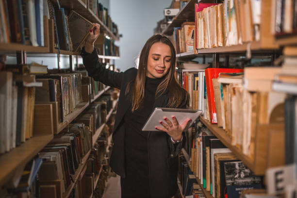 istock The librarian takes a book from the shelf while looking at the digital tablet 1463646986