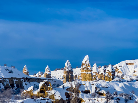 Beautiful view on Göreme Valley. The most important tourist centre for Cappadocia with astonishing rock formations. Historical area covered with snow. Rock hoodoo winter landscape background, copy space.