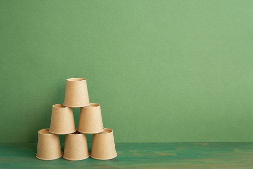 Pyramid stack of brown cup on wooden table. green background. business develop achievement growth concept