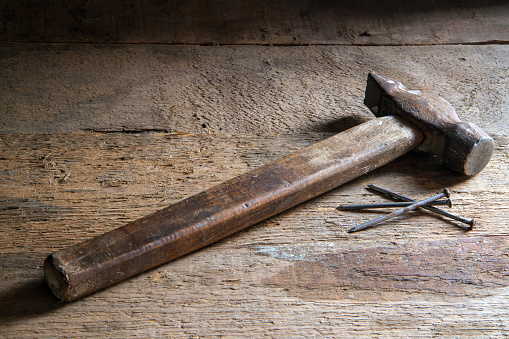 An old hammer on a wooden surface. Hammer and nails on old boards.