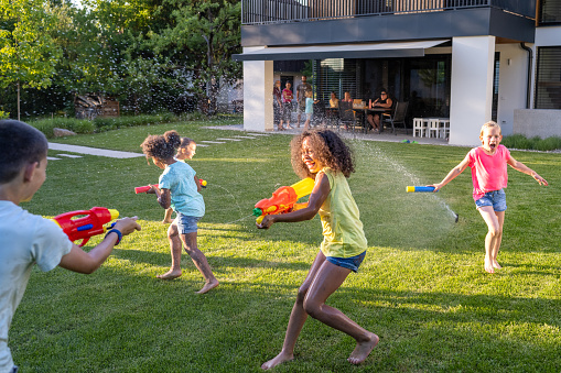 A father with three daughters playing outdoors in the backyard, running.