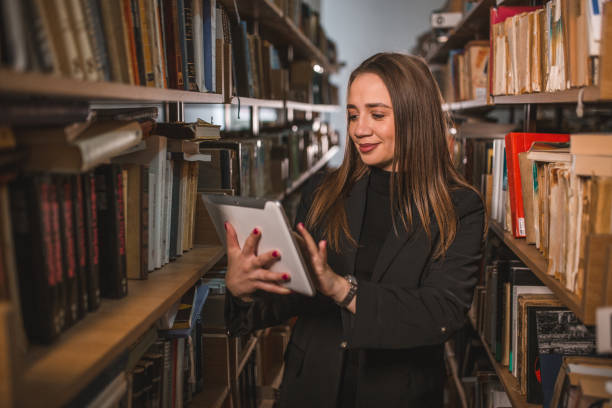istock Cheerful librarian searches books in the library using a digital tablet 1463665571