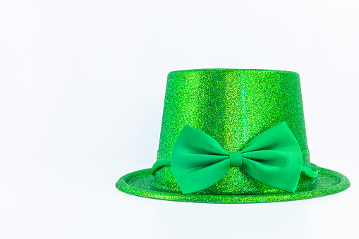 Green Leprechaun hat with glitter and a bow isolated on a white background for Irish St. Patrick's Day holiday and Carnival. Horizontal costume accessory banner with copy space.