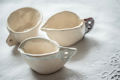 The Beauty of Imperfection of Handmade Clay Coffee Cup on White Tablecloth