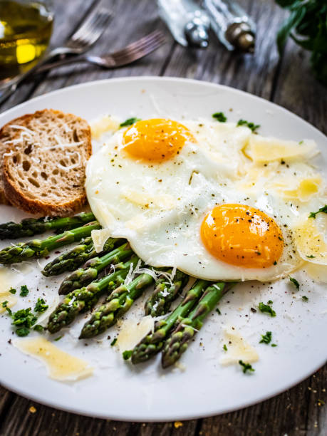 istock Sunny side up eggs with asparagus and parmesan on wooden background 1463668682