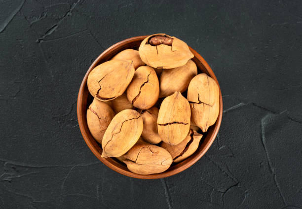 istock Pecan nuts in a bowl on a dark concrete background, top view 1463669783