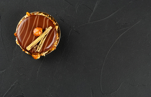 Beautiful chocolate brownie with nuts and salted caramel on a dark concrete background, top view. copy space.