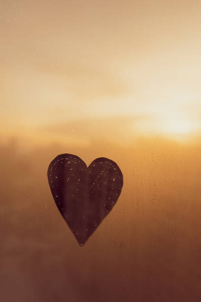 istock Shape heart painted on glass wet window in city, vertical 1463670626