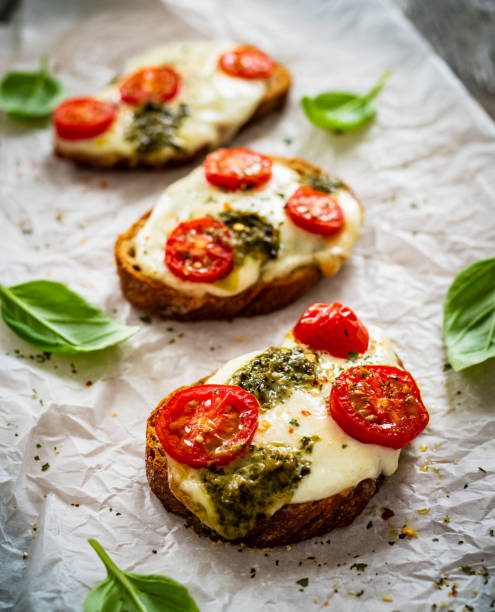 istock Bruschetta breakfast - mozzarella cheese, bread, pesto sauce and tomatoes on wooden table 1463672798