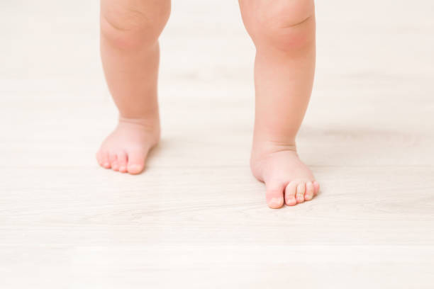 istock Baby barefoot on light wooden floor background. Closeup. First steps. Front view. 1463674024