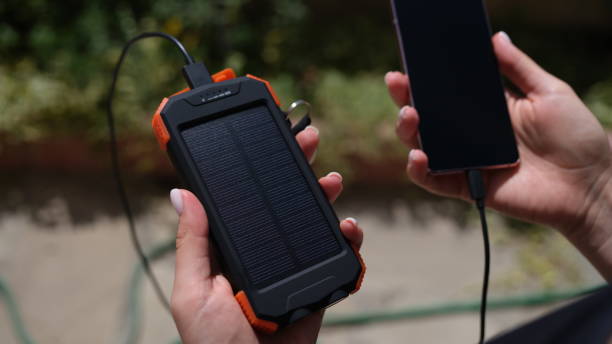 istock Hands holding mobile phone with external battery connected to it with solar battery closeup 1463675059