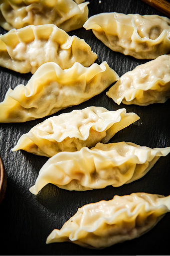 Dumplings gyoza with shrimp on a cutting board. On a black background. High quality photo