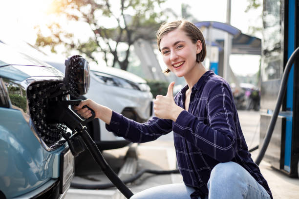 istock African American woman holding a DC - CCS type 2 EV charging connector at EV charging station with her car, woman preparing an EV - electric vehicle charging connector. Eco green concept 1463681795