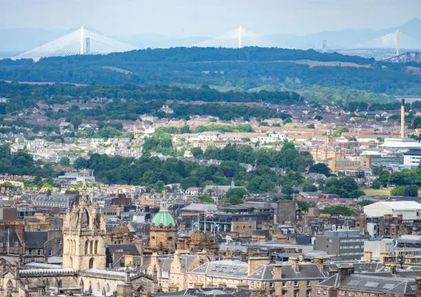 Cityscape of the Capital city of Scotland,with famous Forth Bridges in the far distance and St. Giles church in the foreground,Union Jack flying,sunny summer weather.