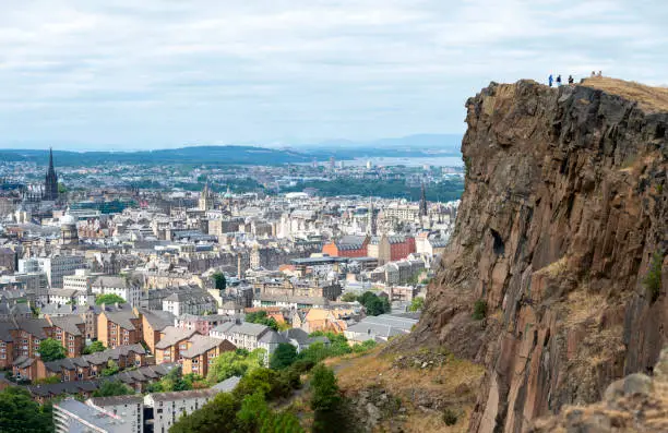 Rocky cliffs in the foreground,dominate the Scotland's capital city,with famous landmarks, Edinburgh Castle set for the Royal MilitaryTattoo,during Fringe Festival,the Hub and St. Mary's Cathedral.