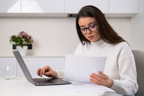 istock Focused woman enters data written in papers into Notebook 1463684876