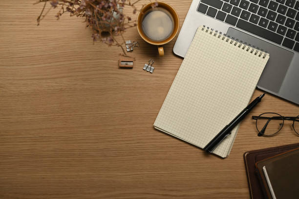 istock Empty notepad, eyeglasses, pen and laptop computer on wooden working desk. Top view with copy space. 1463687436