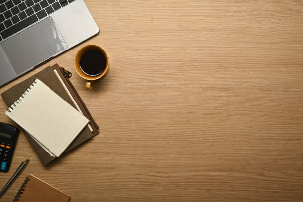 istock Simple workplace with laptop computer, notepad, coffee cup and calculator on wooden table. Top view copy space. 1463687509