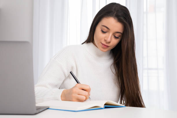 istock Focused young student working on a laptop, preparing for an exam and making notes 1463688432