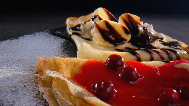 Pancakes topped with cherry syrup, banana and chocolate