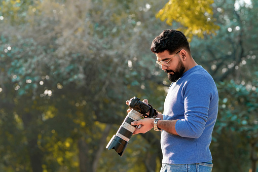 Young indian man using camera equipment at park