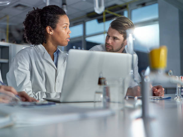 istock Students of science talking while working on laptop in laboratory. 1463696737