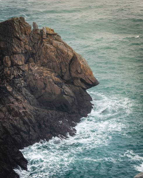 A vertical shot of the waves hitting the rocky cliffs