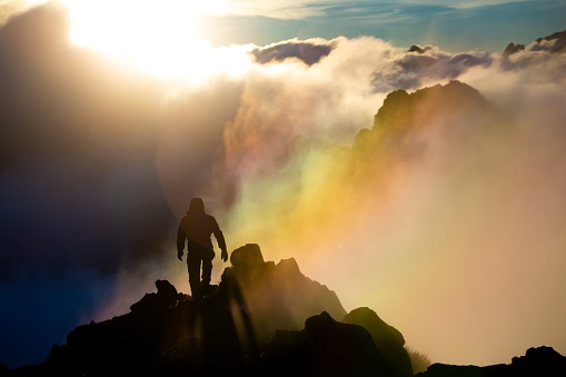 A climber walking along a ridge during a sunrise in the clouds, Tatra mountains