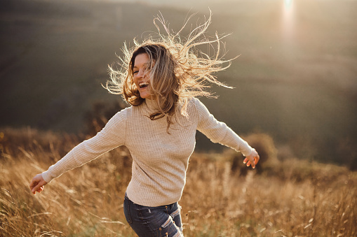 Happy woman having fun with her arms outstretched during autumn day in a meadow. Copy space.