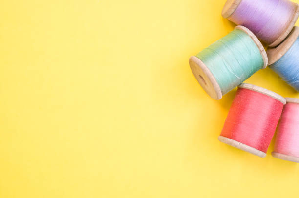 istock Colorful sewing threads isolated on a yellow background with free space for text 1463703296