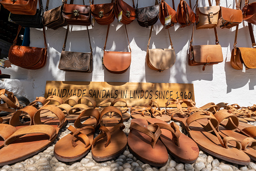 Lindos, Greece - August 2022 : Sandals and handbags for sale in a souvenir and fashion shop in a small tourist village town in Greece