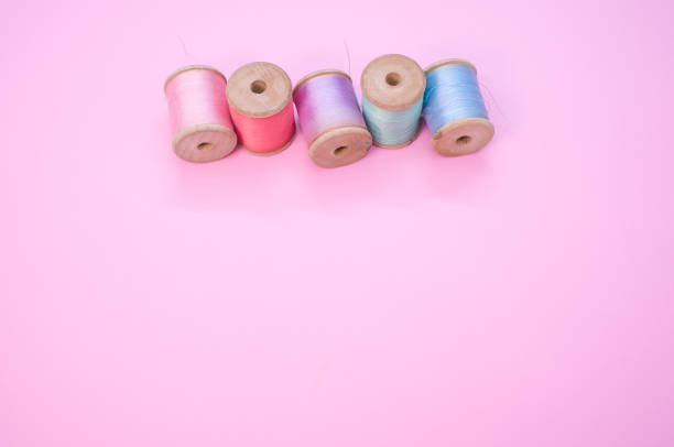 A colorful sewing threads isolated on a pink background with free space for text