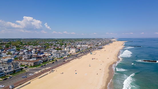 A drone shot of the Belmar Beach and coastal road and buildings on a sunny day in Belmar, New Jersey, USA