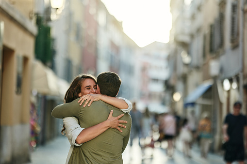 Happy woman enjoying in a hug with her boyfriend on the city street.