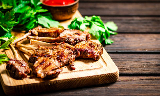 istock Grilled rack lamb on a cutting board with tomato sauce and parsley. 1463708325