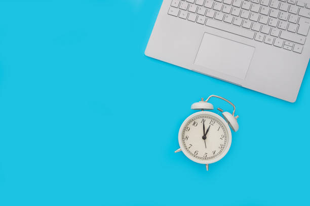 istock Top view of a computer keyboard and an alarm clock on a blue background 1463709462