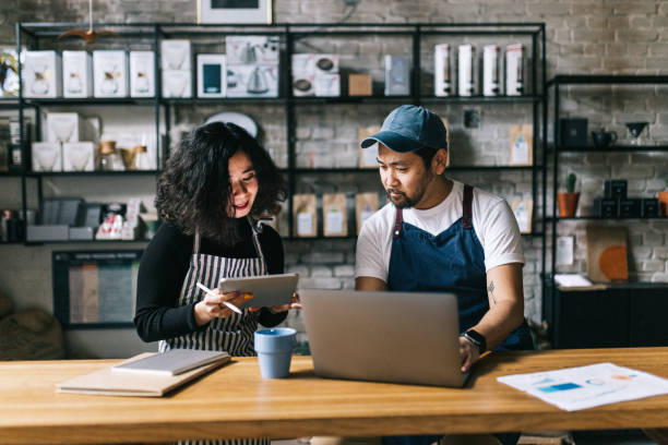 Small business owners working behind cafe counter The owners of this coffee shop engage in a lively discussion, exchanging ideas and making plans for the business. small business stock pictures, royalty-free photos & images