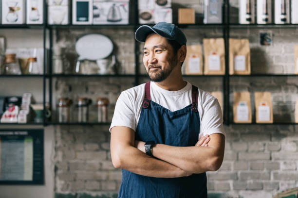 Confident Japanese owner standing at his coffee roastery Standing tall and confident, this small business owner expertly operates his coffee roastery shop, producing top-quality beans. passion stock pictures, royalty-free photos & images