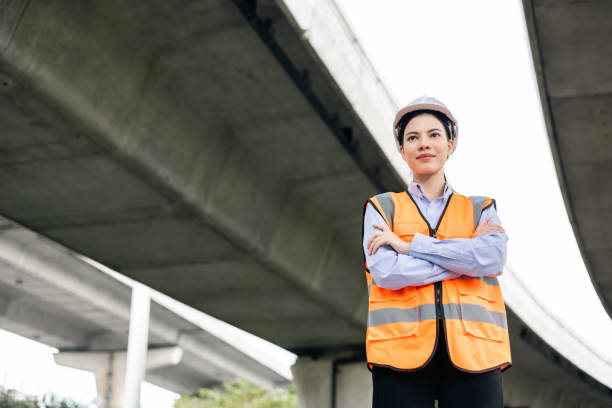 istock Asian engineer worker woman or architect looking construction with white safety helmet in construction site. Standing at highway concrete road site. Progress planning of highway bridge. 1463714048