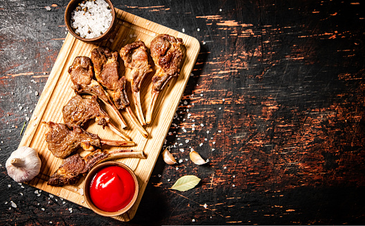 Grilled rack lamb with spices and tomato sauce. Against a dark background. High quality photo