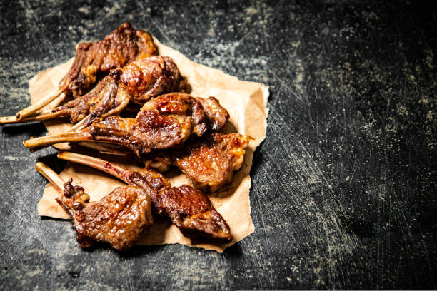 A rack of grilled lamb on paper on the table. On a black background. High quality photo