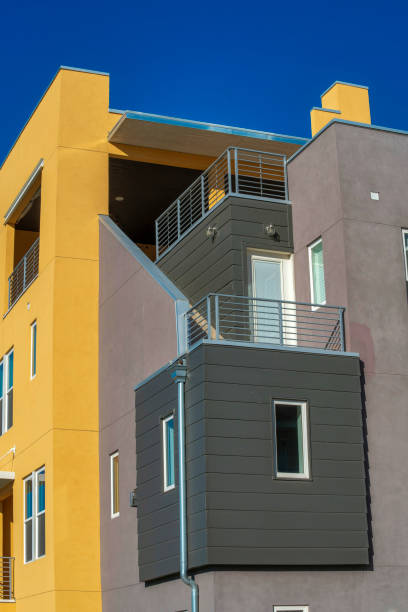 istock Modern building on with yellow and gray walls with windows and blue sky above it 1463715962