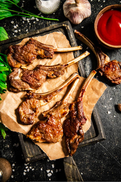 istock Grilled lamb rack on a cutting board with herbs and tomato sauce. 1463715972