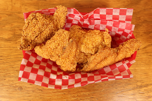 A top view of fried catfish in a basket on a wooden table
