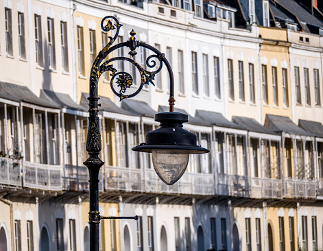 A closeup of a street lamp with a residential building with balconies in the blurry background