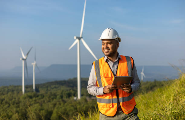 istock Engineer India man working with tablet at windmill farm Generating electricity clean energy. Wind turbine farm generator by alternative green energy. Asian engineer checking control electric power 1463723939