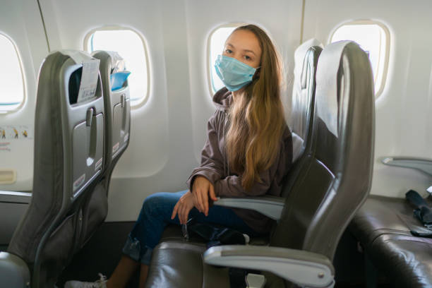 istock Pretty blonde woman wearing face mask during flight on plane 1463730616