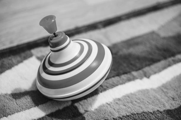 A grayscale shot of a spinning top on a soft carpet