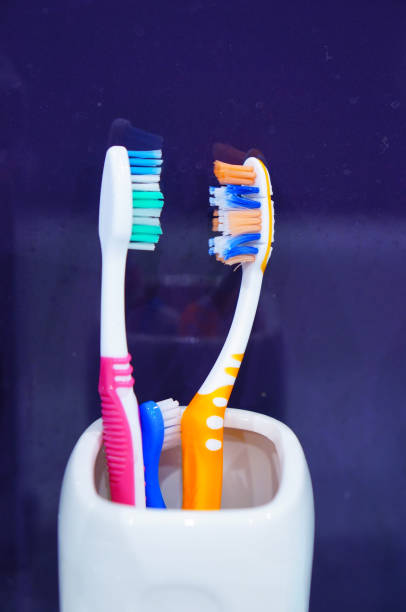 istock Vertical shot of three toothbrushes in a white cup 1463742474